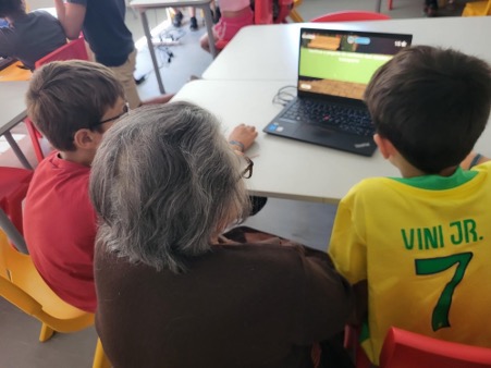older adult and children around a computer